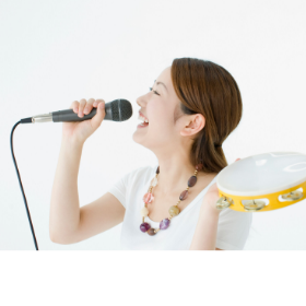 タンバリンとマイクを持って歌う女性